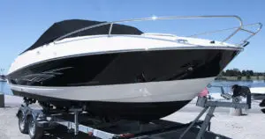 Modern black and white motorboat parked on a boat trailer near a marina
