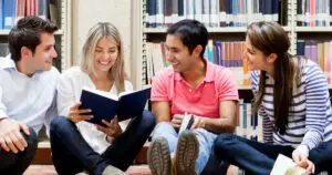 Group of diverse college students studying together on the floor of a library