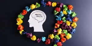 Mental health concept showing a human head silhouette surrounded by colorful crumpled paper