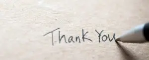 Handwritten Thank You note on textured kraft paper with pen