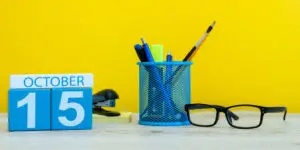 October 15 block calendar with office supplies on a desk