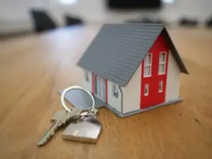 Miniature model house next to house keys on a wooden table