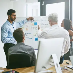 Diverse business team presenting strategy on a whiteboard in a modern office