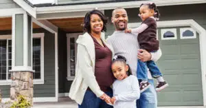 Happy Black family standing outside their new suburban home