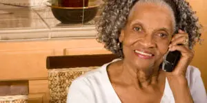 Smiling senior Black woman talking on a cordless landline phone at home