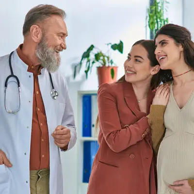 Senior male doctor consulting with a happy pregnant couple in a clinic