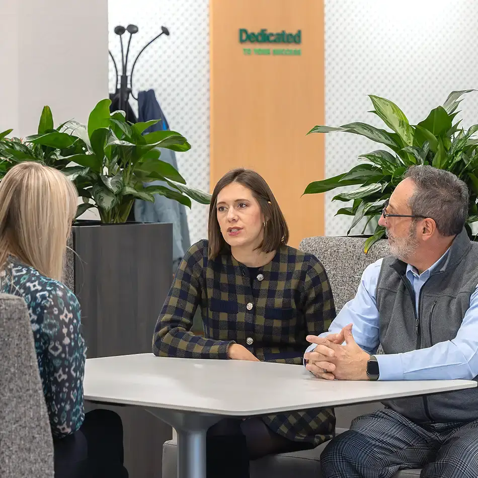 Walsh employees sitting and chatting together. A sign int he background reads "Dedicated to Your Success"